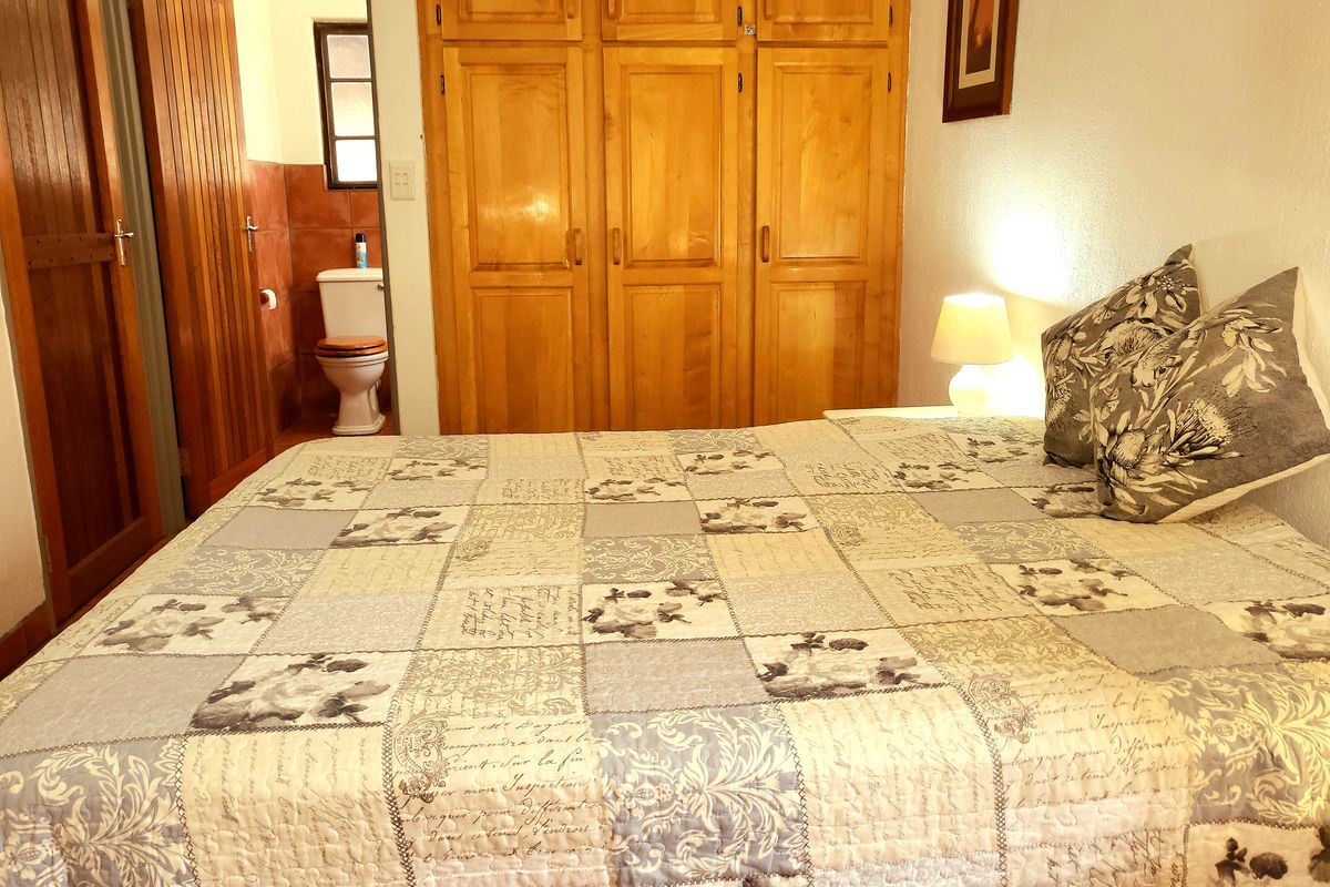 A bedroom featuring built-in wooden cupboards and an adjoining en-suite bathroom with tiled finishes.
