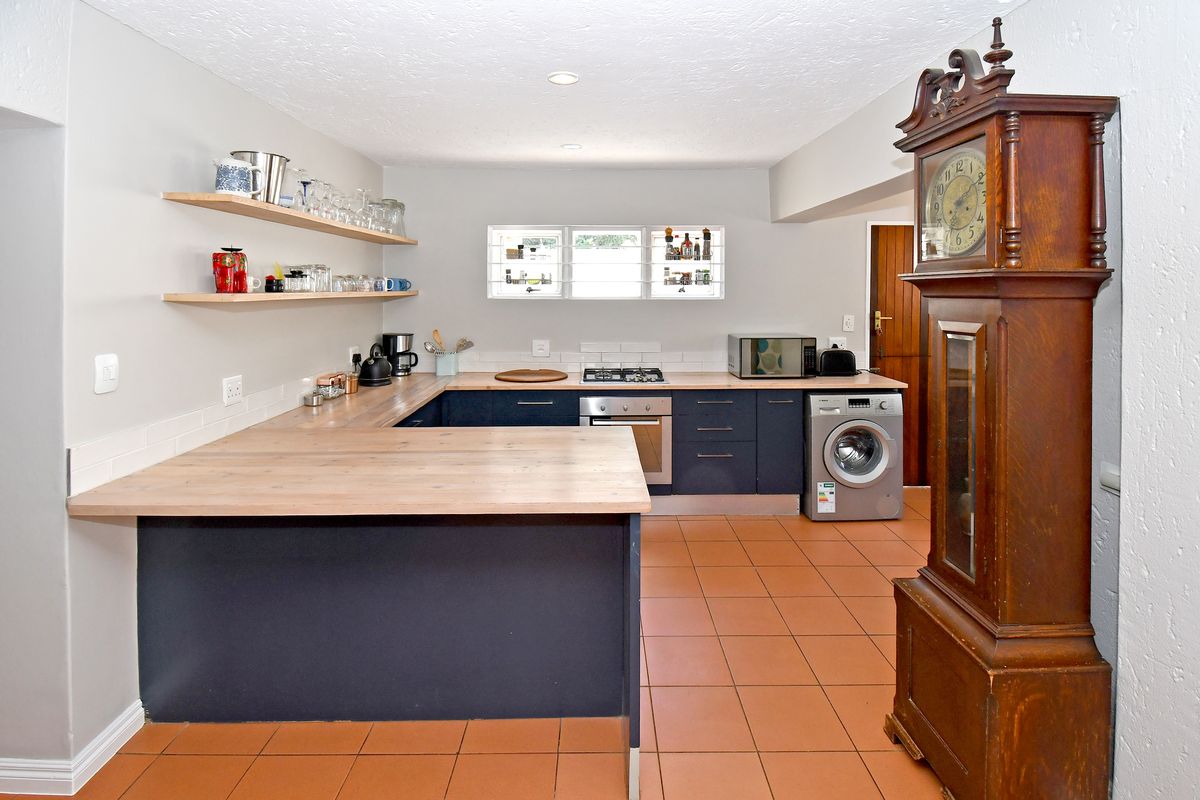 Modern kitchen featuring dark blue cabinetry, light wood countertops, tiled flooring, and integrated appliances, offering a functional and stylish cooking space.