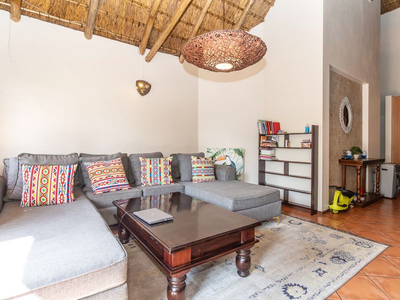 Living room featuring a high vaulted thatched roof with exposed timber rafters and terracotta floor tiles.