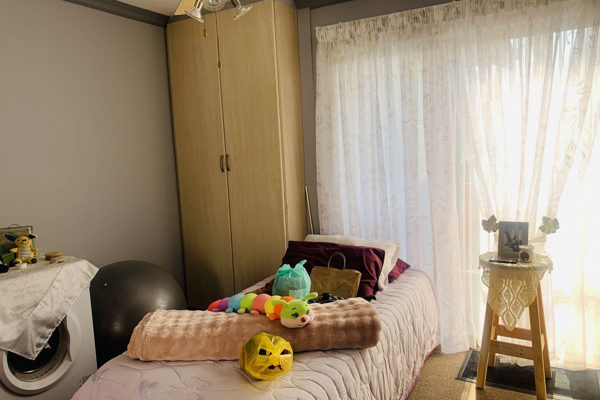 A bedroom featuring a built-in wardrobe, ceiling fan, and sliding glass door providing natural light and access to the exterior.