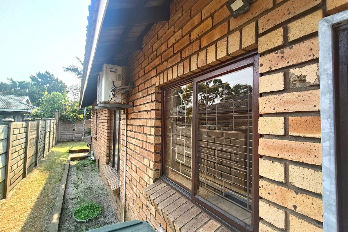 Side exterior view of the duet property featuring face brick walls, security-fitted windows, and an external air conditioning unit.