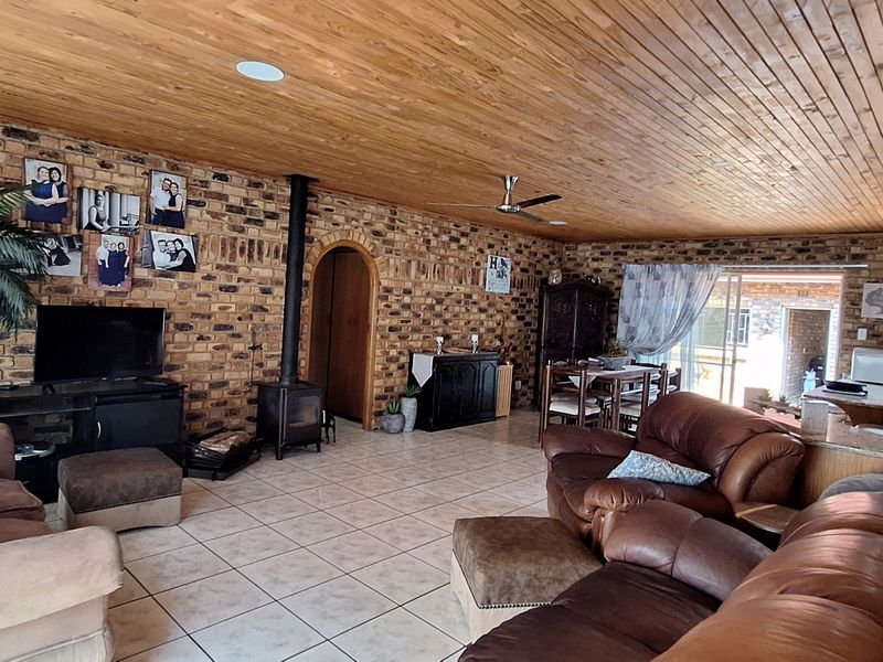 Spacious open-plan living area featuring exposed brick walls, a timber ceiling, and a freestanding wood-burning fireplace, creating a warm and rustic atmosphere.