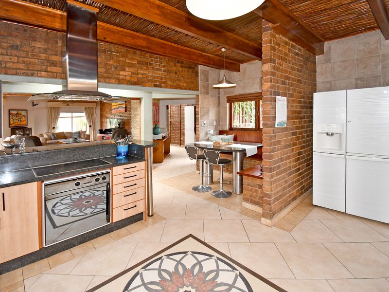 Spacious kitchen featuring exposed brick walls, timber beam ceilings, granite countertops, built-in oven, and a cozy integrated breakfast nook with tiled flooring.