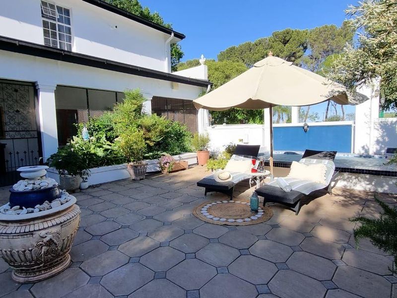 A well-maintained paved patio area featuring a built-in water feature, raised garden beds, and a small plunge pool, perfect for outdoor relaxation.