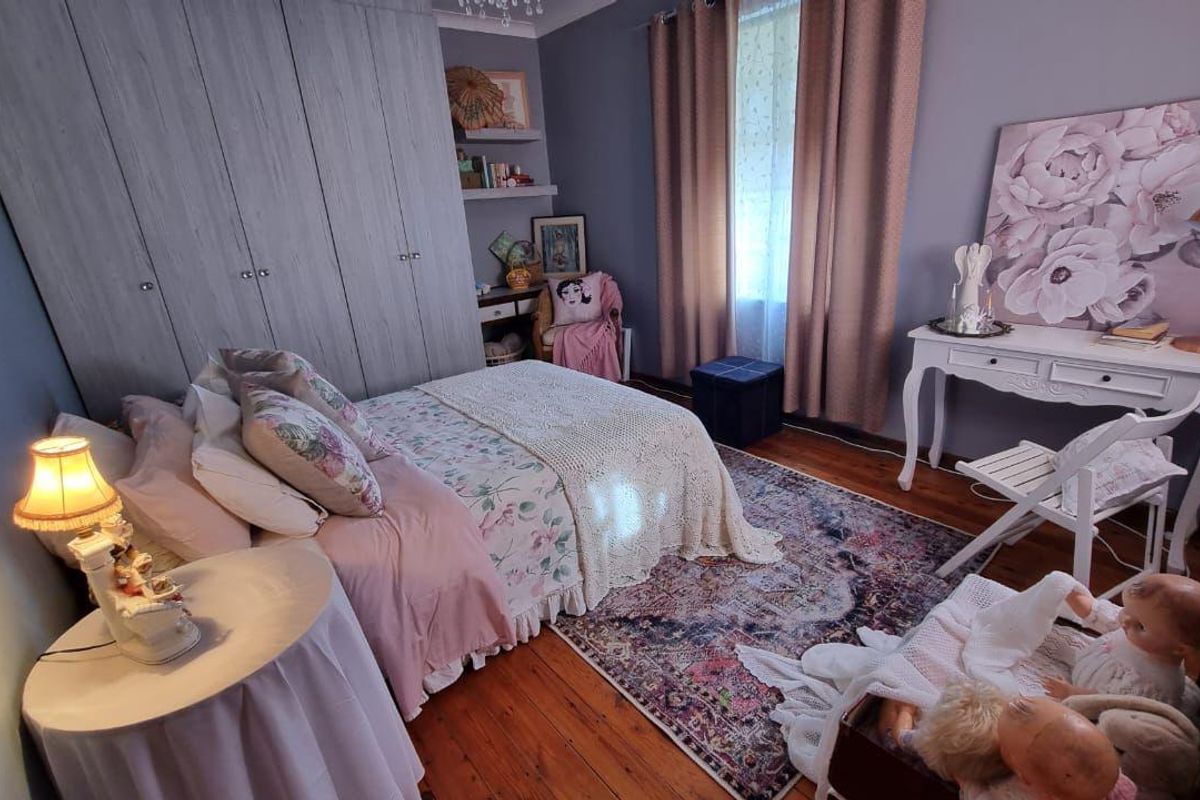 A cozy bedroom featuring hardwood flooring, built-in cupboards, and integrated shelving, offering a warm and functional living space.