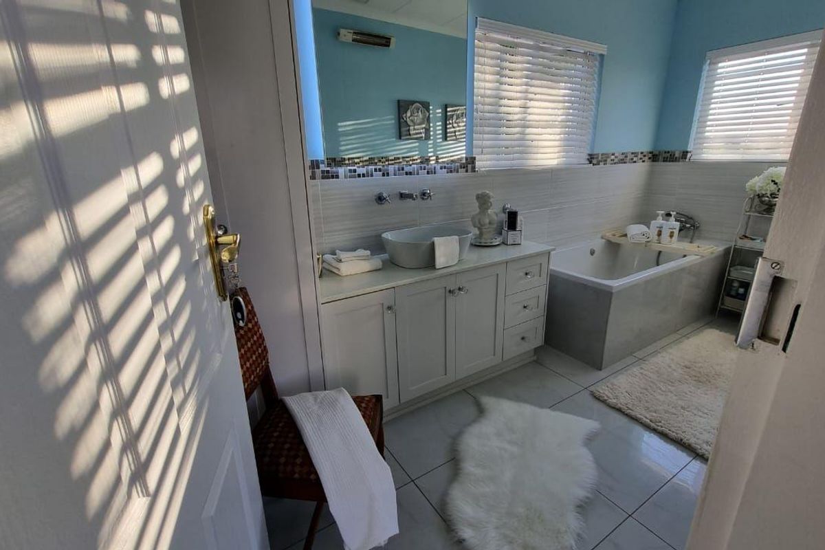 A well-maintained bathroom featuring a modern vessel sink on a vanity cabinet, a built-in bathtub, and tiled finishes with natural light.