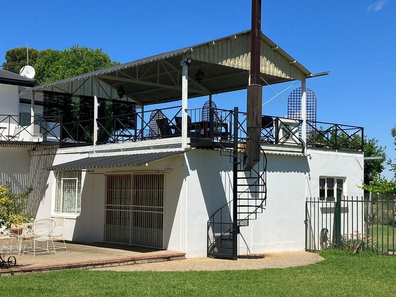 An elevated outdoor patio area featuring a metal roof, black metal railings, and a spiral staircase providing access to the ground level.