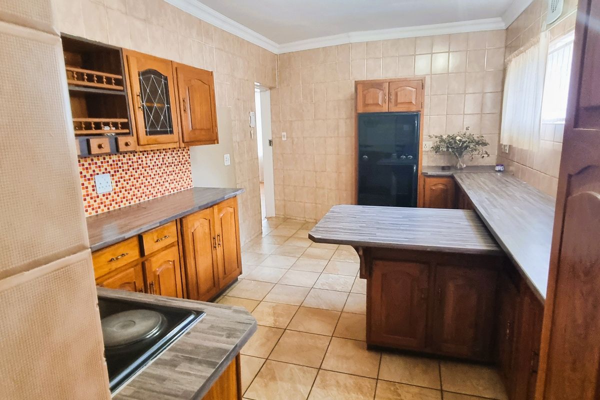 A functional kitchen featuring traditional wooden cabinetry, laminate countertops, and full-height ceramic wall tiling, offering a classic layout with ample storage space.