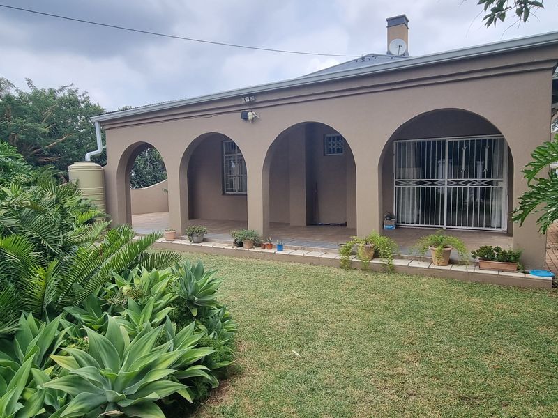A covered patio area featuring classic arched columns, tiled flooring, and direct access to the garden, providing a sheltered outdoor living space.