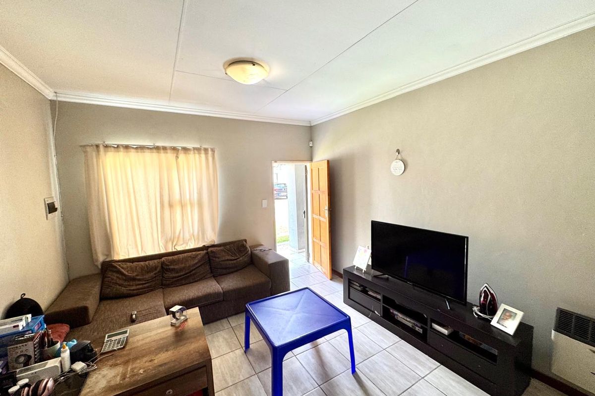A functional living room featuring tiled flooring, crown molding, and direct access to the exterior.