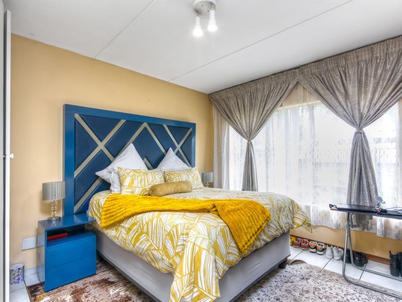 A well-lit bedroom featuring tiled flooring and a built-in cupboard, offering a functional and comfortable living space.