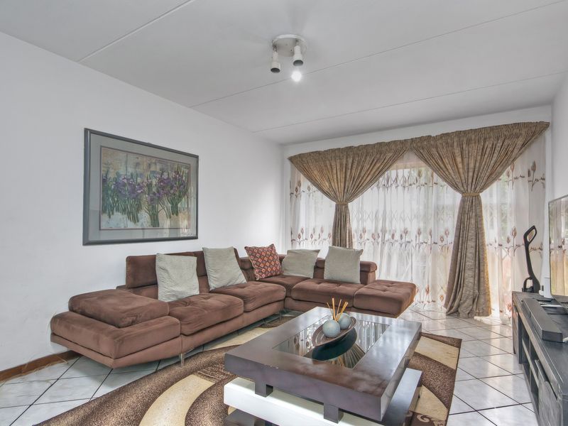 A well-lit living room featuring tiled flooring and large windows with curtains, providing a comfortable and functional space for relaxation.