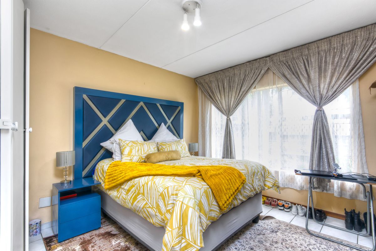 A well-lit bedroom featuring tiled flooring and a built-in cupboard, offering a functional and comfortable living space.