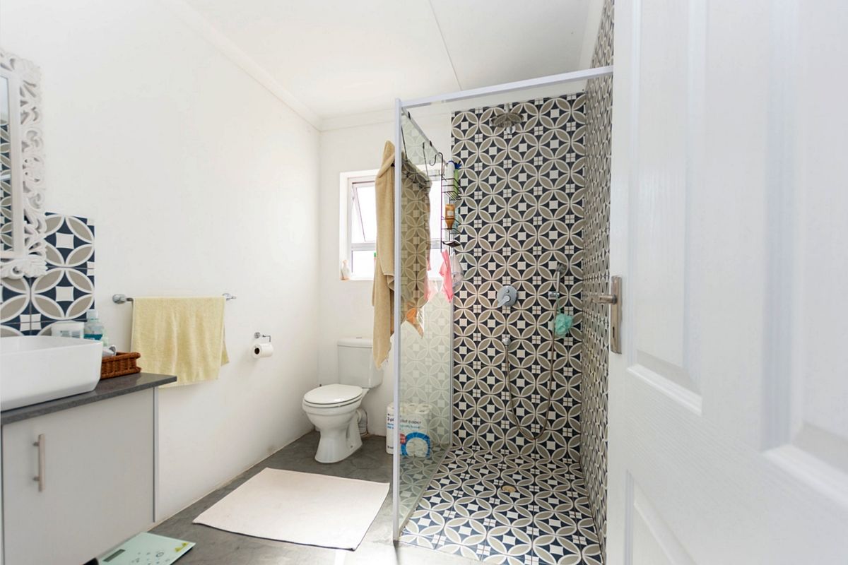 Modern bathroom featuring a walk-in shower with decorative patterned tiling, a vanity with a vessel sink, and a toilet.