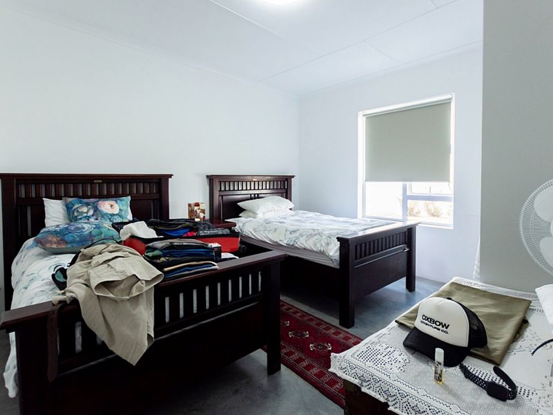 A bedroom featuring neutral walls, tiled flooring, and a roller blind on the window.
