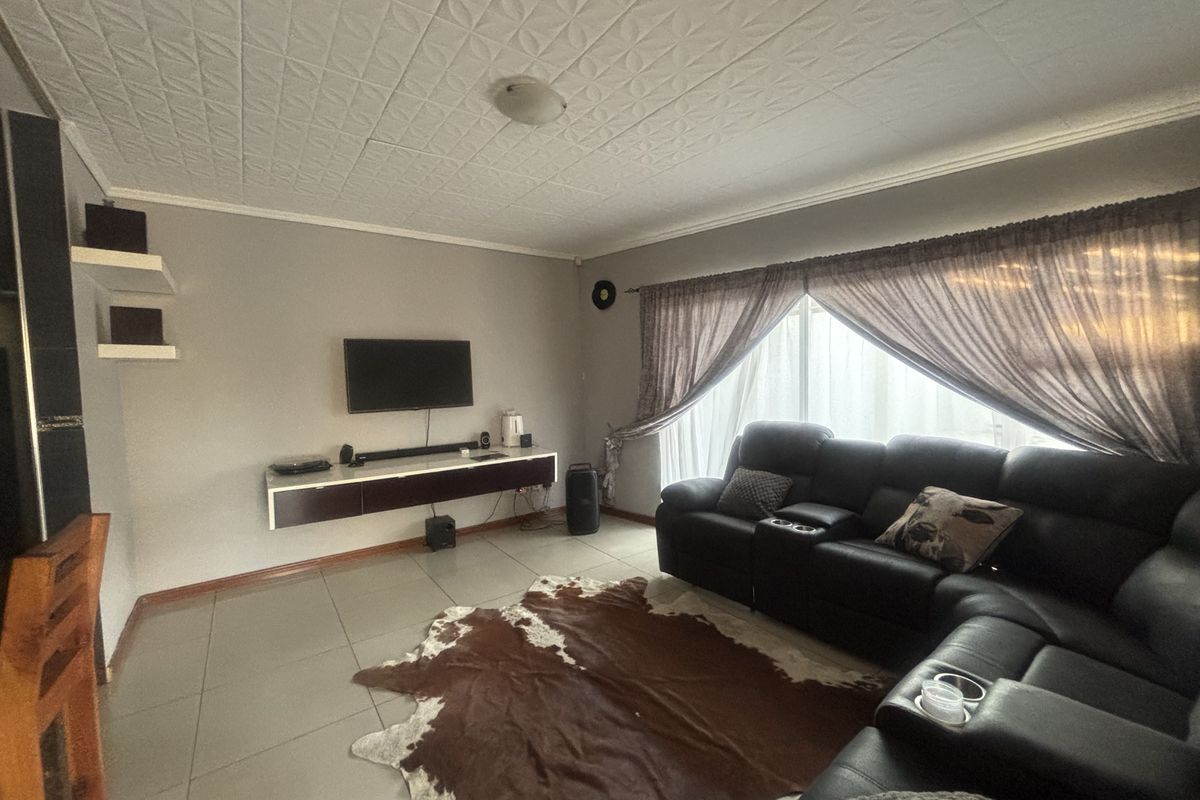 A living room featuring tiled flooring, a textured ceiling, and a wall-mounted floating media console.