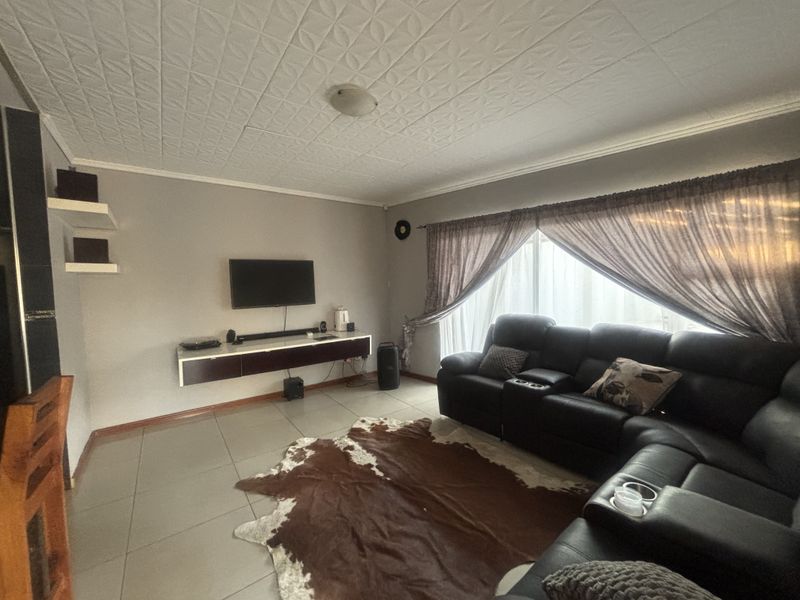 A living room featuring tiled flooring, a textured ceiling, and a wall-mounted floating media console.