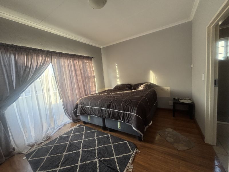 A bedroom featuring laminate flooring, a ceiling light fixture, and a sliding glass door providing access to the exterior.