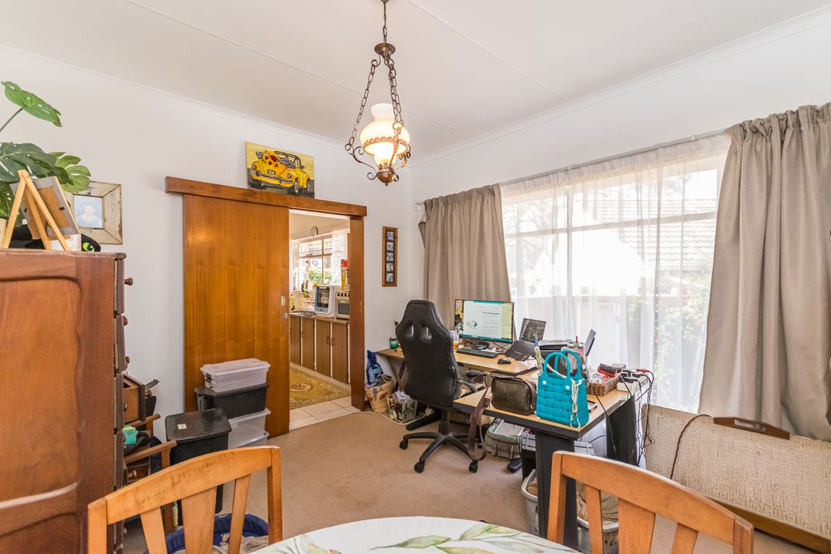 A living room space featuring a sliding wooden door leading to the kitchen, large window with curtains, and carpeted flooring.