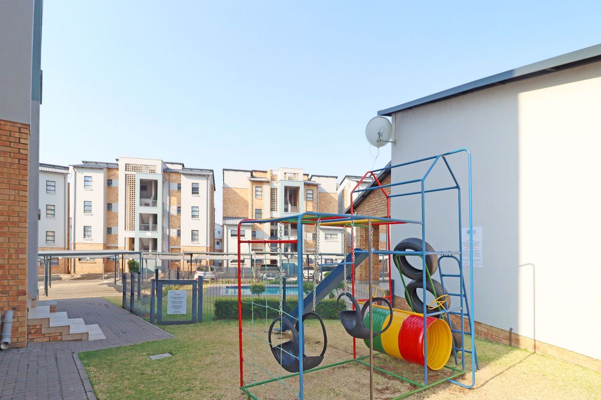 Exterior view of an apartment complex courtyard featuring a paved walkway, brick building facade, and communal outdoor space.