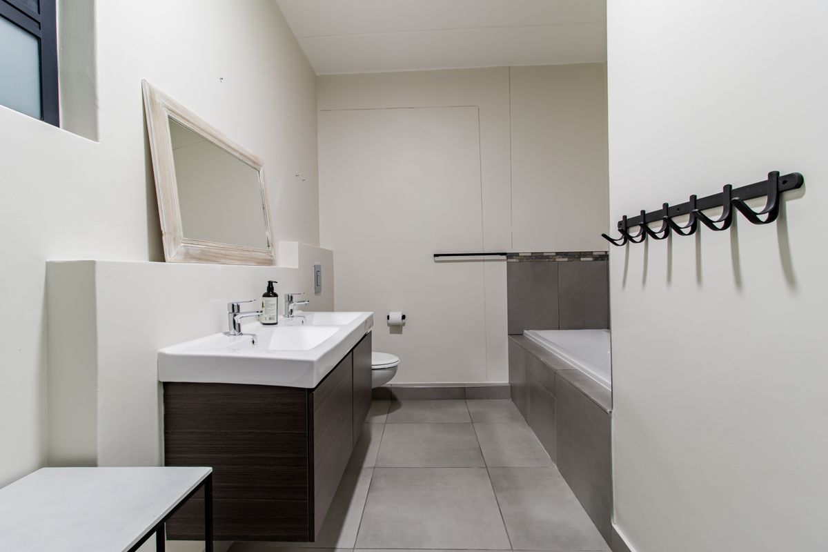 Modern bathroom featuring a double vanity, built-in bathtub, and neutral tiled finishes, providing a clean and functional space.