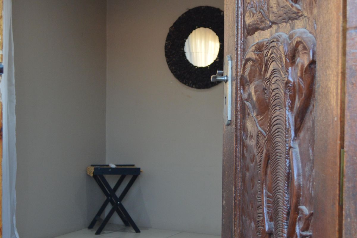 A view into a bedroom featuring tiled flooring, recessed lighting, and a decorative carved wooden door.