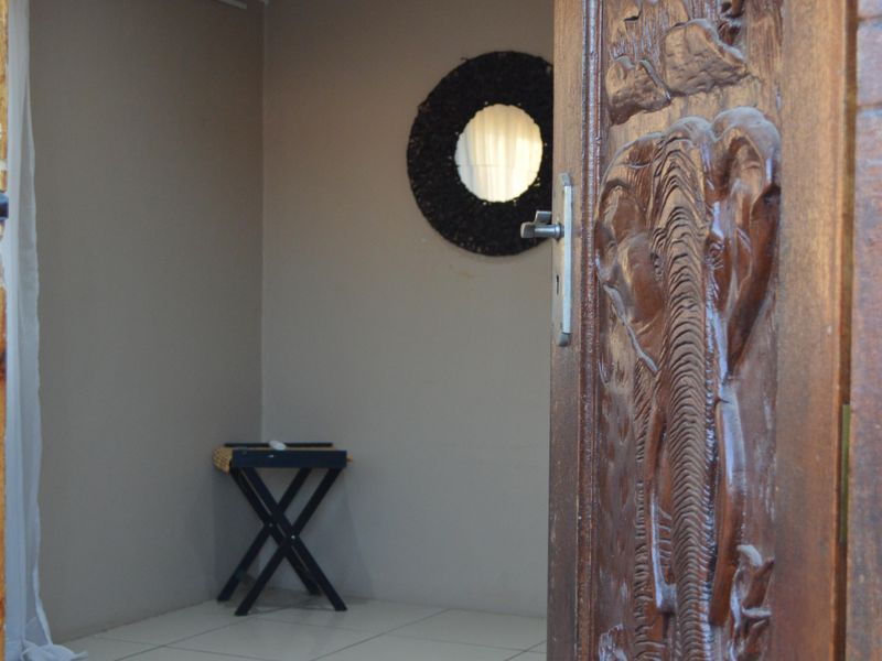 A view into a bedroom featuring tiled flooring, recessed lighting, and a decorative carved wooden door.
