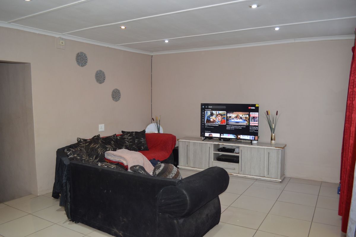A functional living room featuring tiled flooring and recessed ceiling lighting, providing a neutral base for potential interior updates.