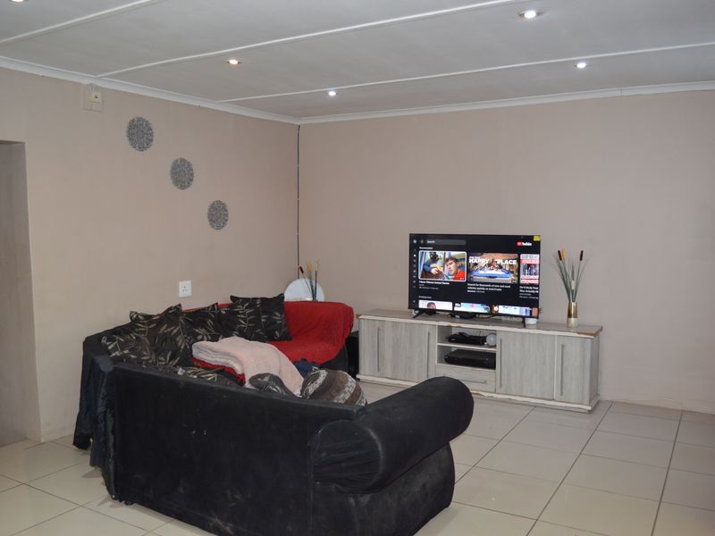A functional living room featuring tiled flooring and recessed ceiling lighting, providing a neutral base for potential interior updates.