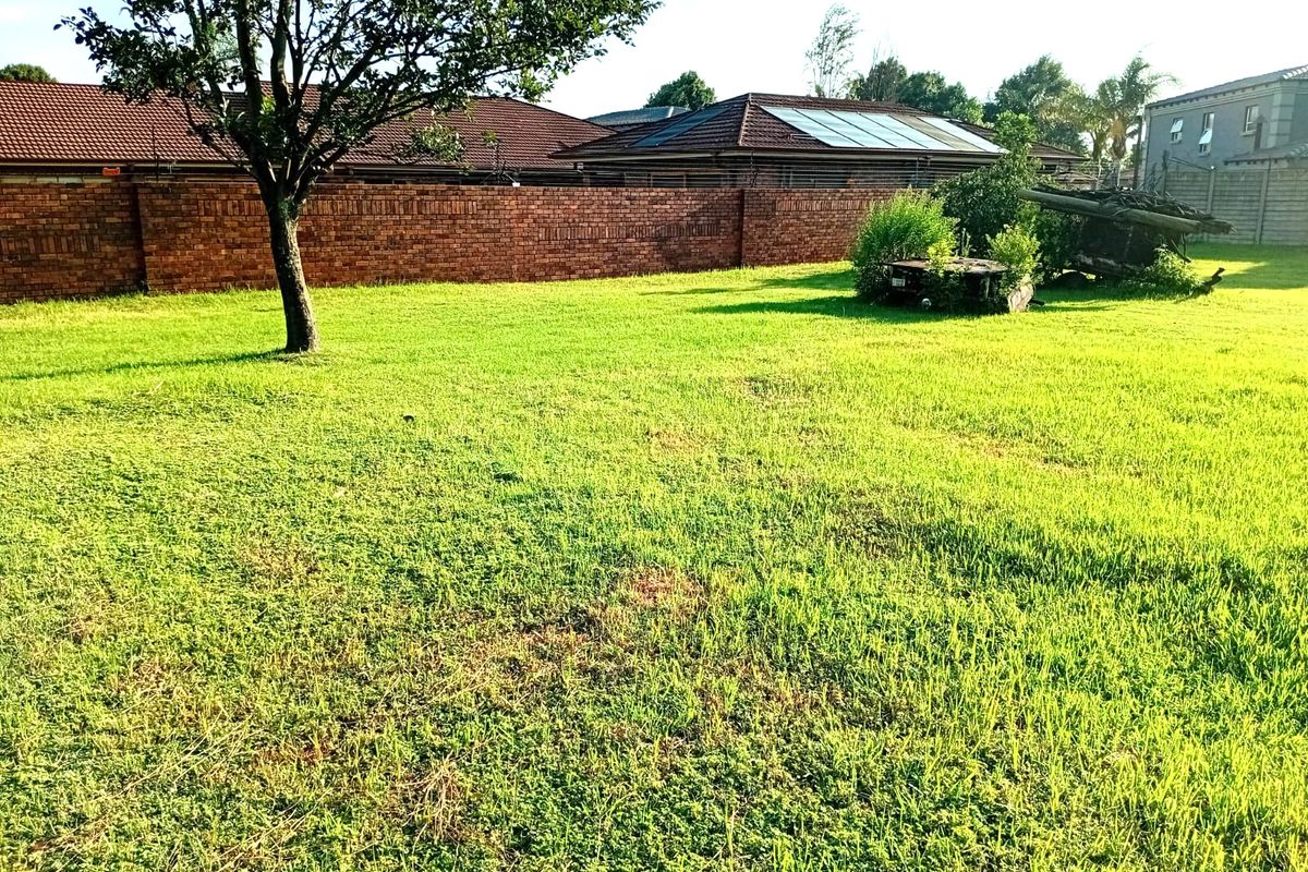 A spacious vacant residential plot featuring established perimeter brick walling and mature trees, offering a blank canvas for future development.