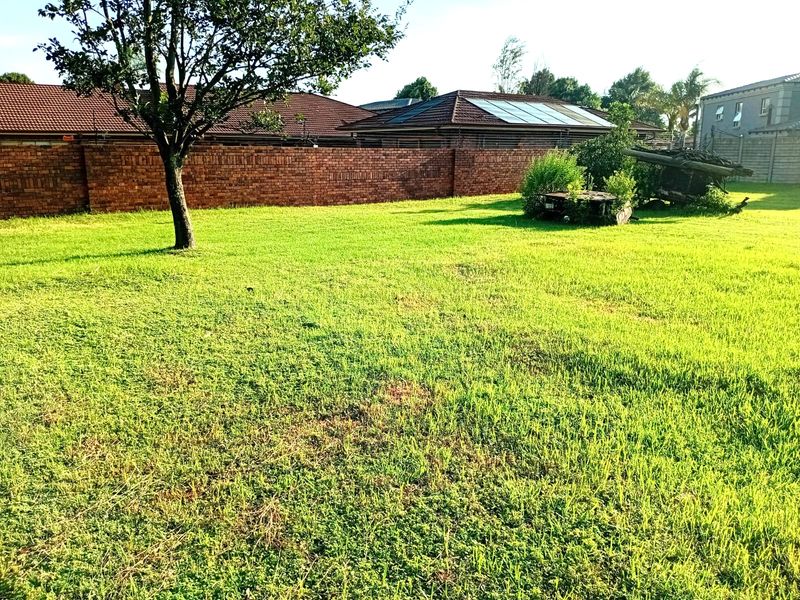 A spacious vacant residential plot featuring established perimeter brick walling and mature trees, offering a blank canvas for future development.