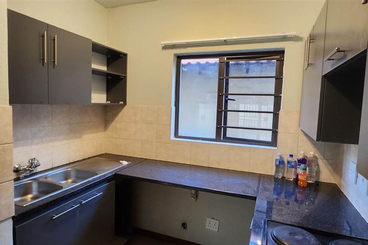 A functional kitchen featuring dark cabinetry, granite countertops, a double stainless steel sink, and a built-in electric hob.
