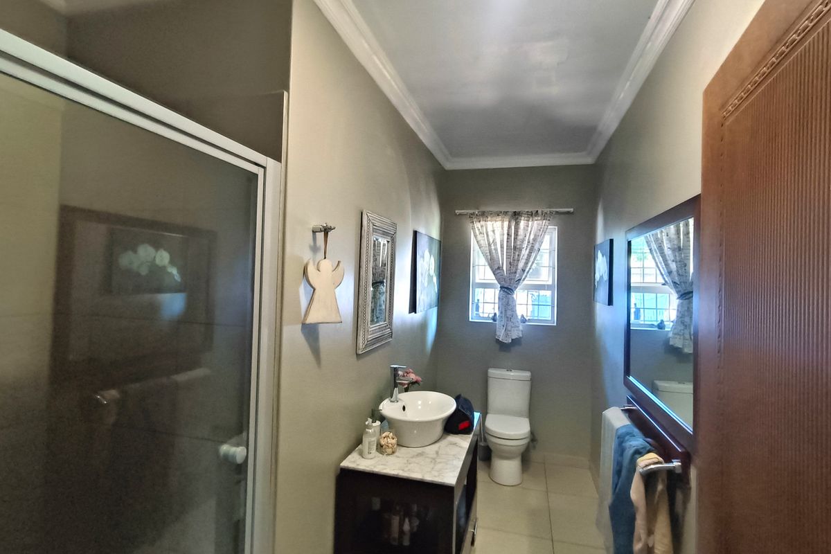 A well-maintained bathroom featuring a vessel sink on a marble-topped vanity, a glass-enclosed shower, and a toilet, finished with crown molding.