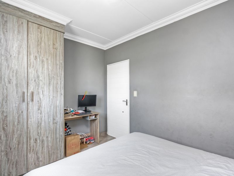 A bedroom featuring grey walls, crown molding, and a built-in wood-grain wardrobe.