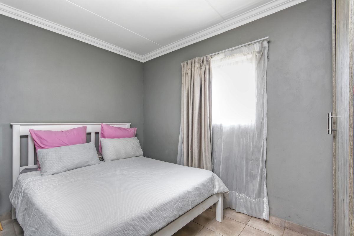 A compact bedroom featuring grey painted walls, tiled flooring, decorative ceiling cornice, and a built-in wardrobe.
