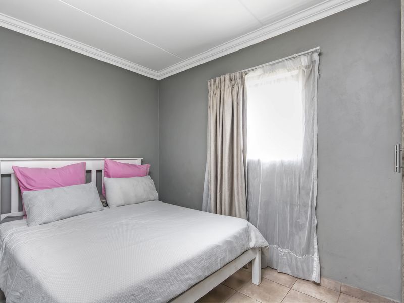 A compact bedroom featuring grey painted walls, tiled flooring, decorative ceiling cornice, and a built-in wardrobe.