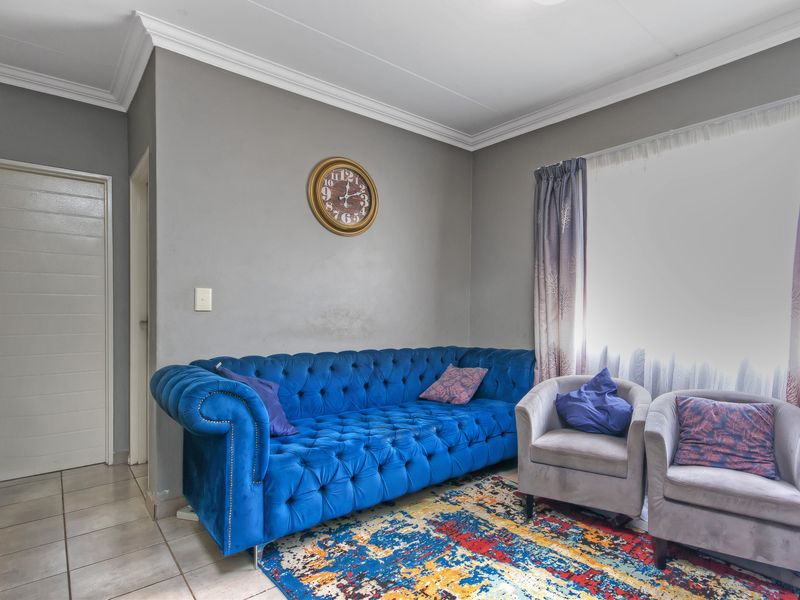 A living room featuring neutral grey walls, crown molding, and tiled flooring, providing a functional space for relaxation.