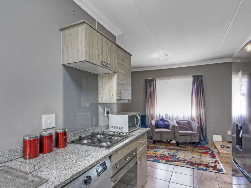 Open-plan kitchen and living area featuring granite countertops, gas hob, built-in oven, and tiled flooring throughout.
