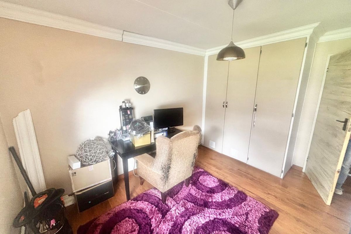 A bedroom featuring laminate flooring, built-in cupboards, and decorative ceiling cornice, offering a functional space with neutral wall tones.