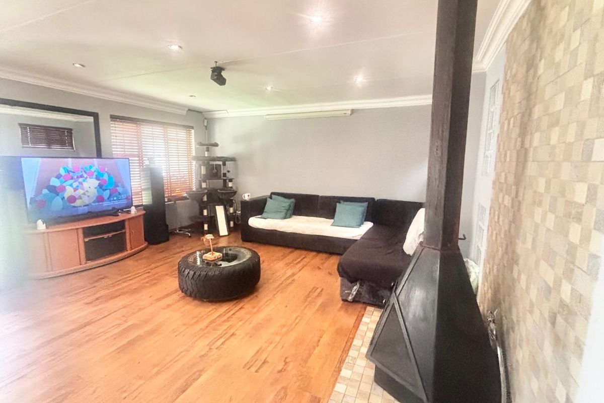 Spacious living room featuring hardwood flooring, a prominent freestanding fireplace, and a decorative tiled feature wall with recessed lighting.
