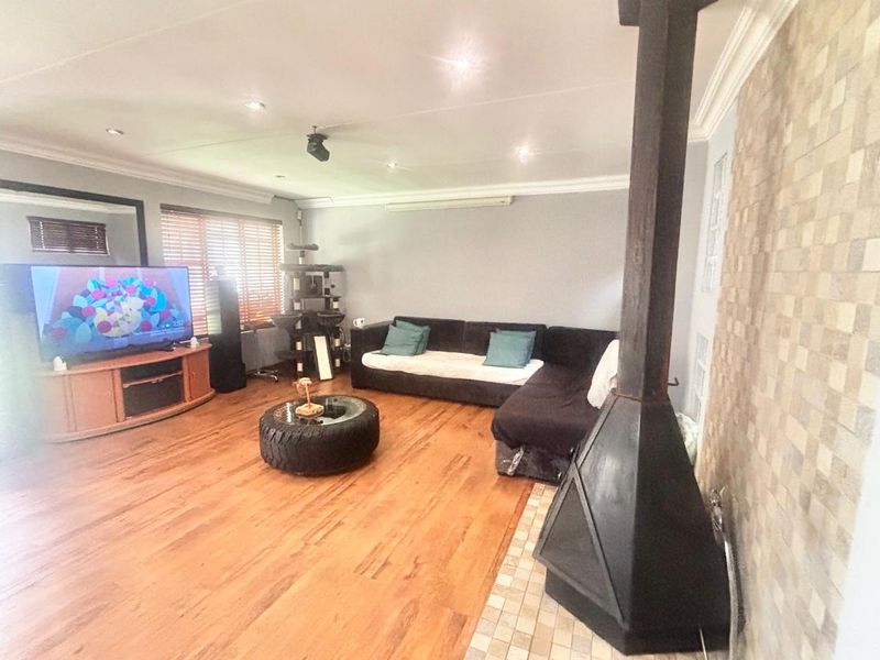 Spacious living room featuring hardwood flooring, a prominent freestanding fireplace, and a decorative tiled feature wall with recessed lighting.