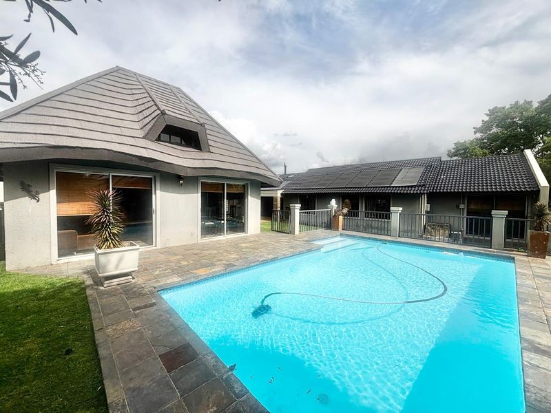 Outdoor pool area featuring stone paving, a swimming pool with solar heating panels, and direct access to the main dwelling via sliding glass doors.