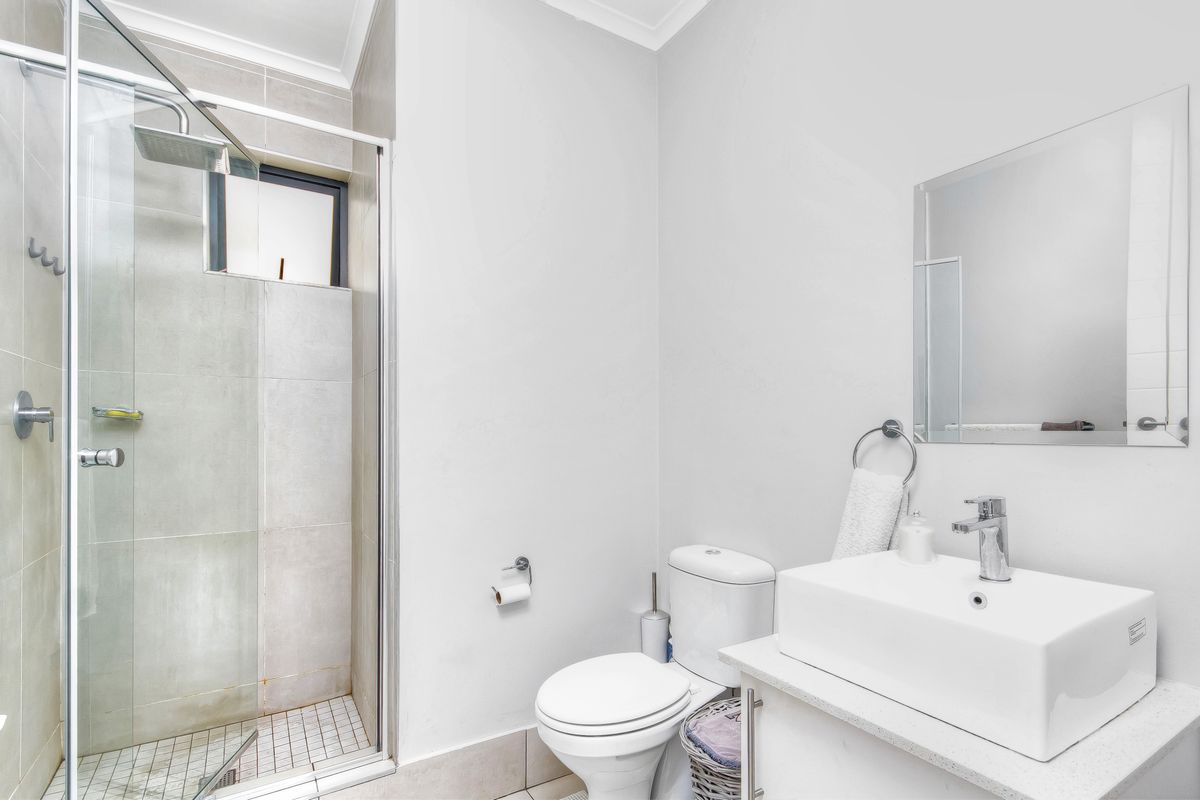 Modern bathroom featuring a glass-enclosed shower, a contemporary vanity with a vessel sink, and a wall-mounted mirror.