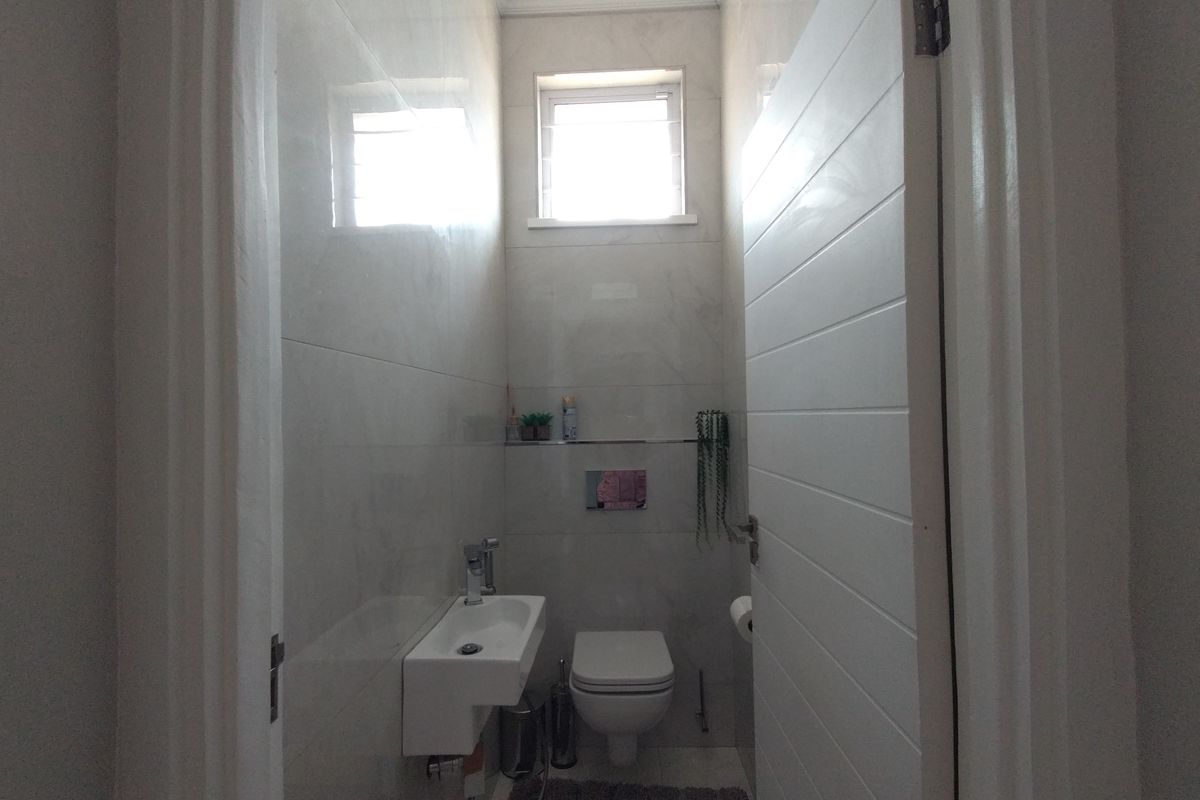 A compact, modern bathroom featuring a wall-hung toilet, wall-mounted basin, and floor-to-ceiling tiling.