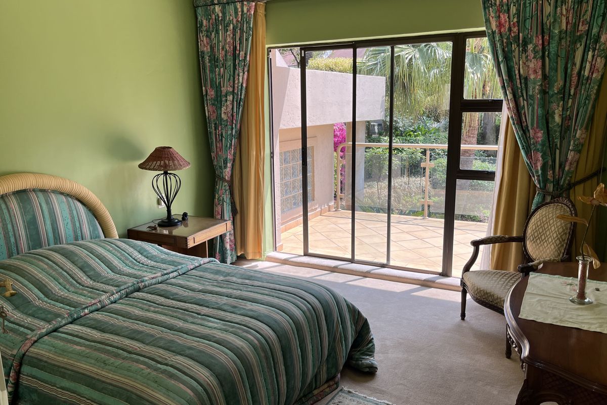 A bedroom featuring sliding glass doors that open onto a private balcony, providing natural light and outdoor access.