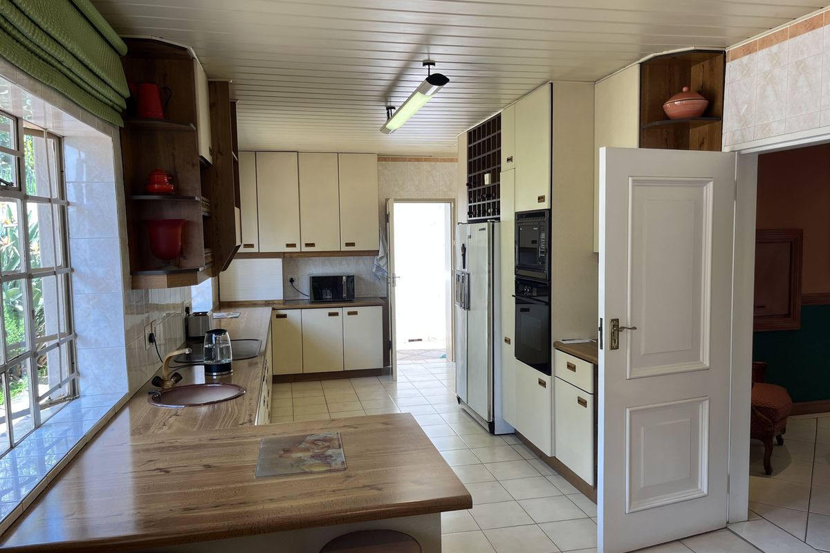 A functional kitchen featuring built-in cabinetry, integrated oven and microwave, tiled flooring, and a breakfast bar area with natural light.