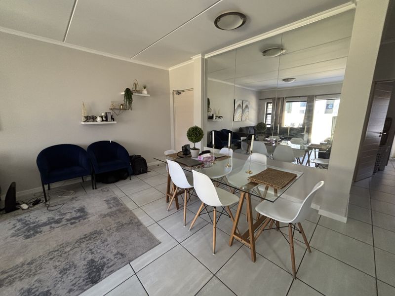 Dining area featuring tiled flooring and a large mirrored wall, creating a bright and spacious atmosphere.