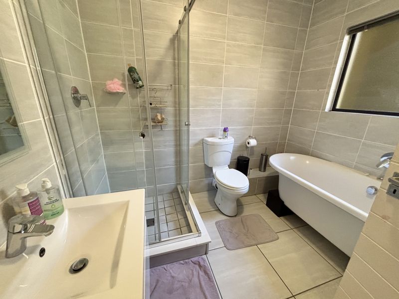 Modern bathroom featuring a freestanding bathtub, separate glass-enclosed shower, ceramic toilet, and wall-mounted basin with neutral tiled finishes.