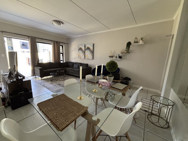 Open-plan living and dining area featuring neutral wall tones, tiled flooring, and a large sliding door providing access to the outdoor space.