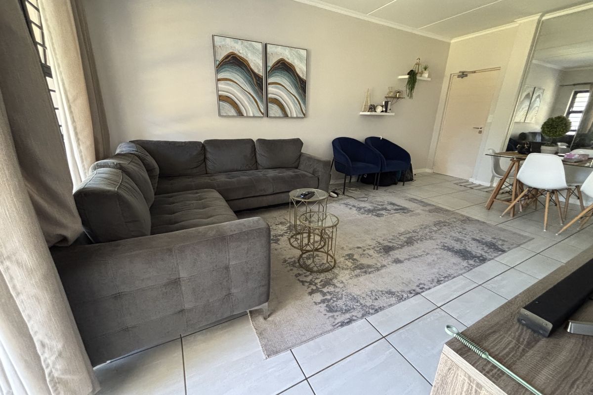 A well-maintained living room featuring neutral tiled flooring and a spacious layout, providing a comfortable and functional living area.